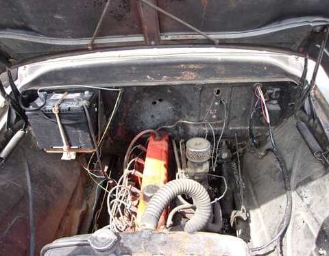 Rusty vintage car engine bay with orange motor