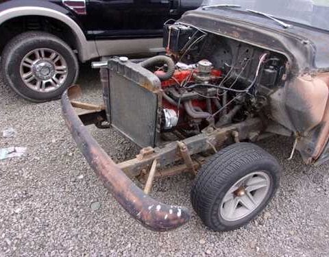 Rusty vintage car with exposed engine and bumper
