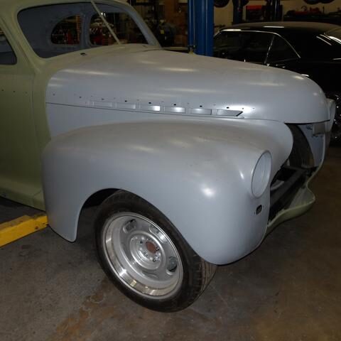 A classic car front fender and wheel in a garage setting.
