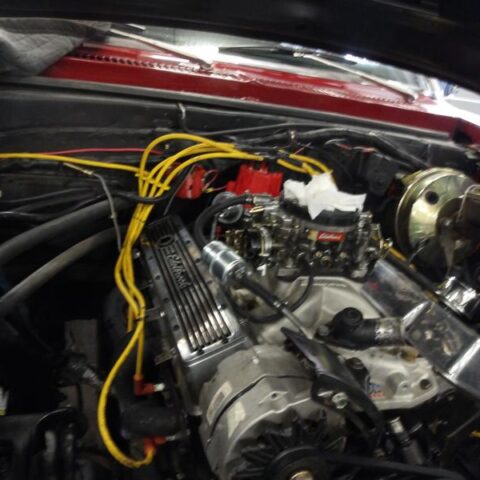 Close-up of a car engine with yellow ignition wires and a red distributor cap.
