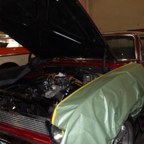 Classic car with hood open, undergoing engine work.