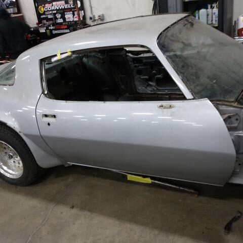 Silver vintage sports car in a garage with the door open.