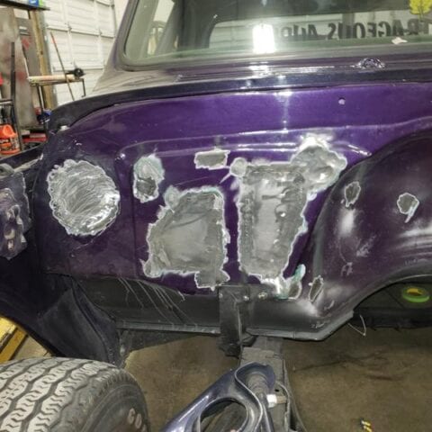 Purple truck fender with patched metal repairs