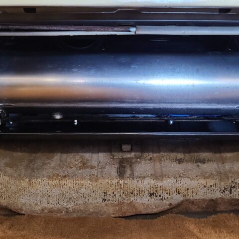 Black cylindrical object with screws on a rough surface.