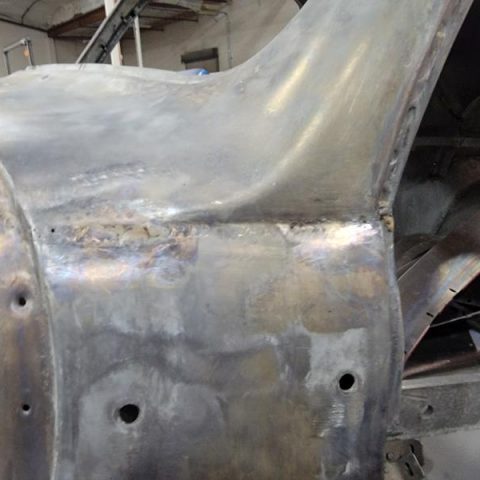 Welded bare car body panel in workshop