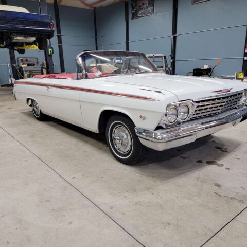 Classic white convertible car parked indoors with red interior.