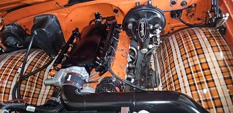 Close-up of an orange engine with black components and a shiny air filter.