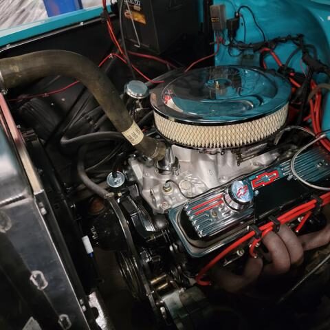 Close-up of a clean car engine with a round air filter and red valve covers.