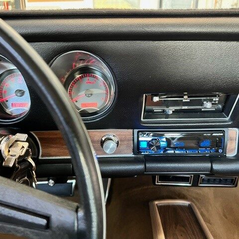 Classic car dashboard with vintage gauges and modern stereo system.