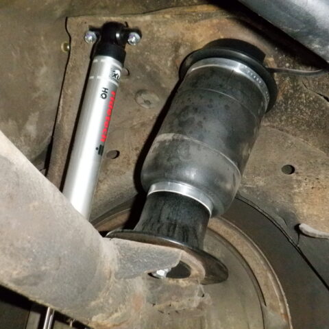 Close-up of a car suspension showing an air spring and shock absorber.