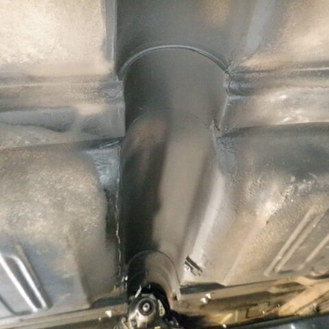 Close-up of a car's undercarriage showing the exhaust system and surrounding metal frame.