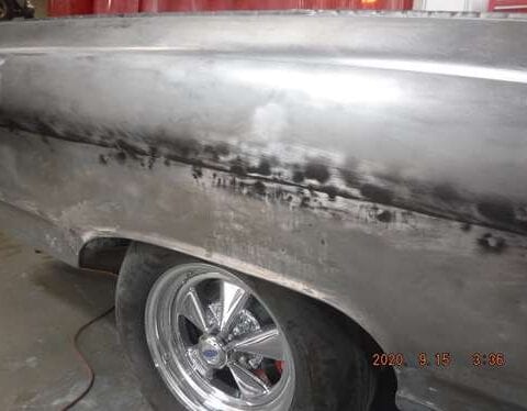 Bare-metal classic car side with chrome wheel