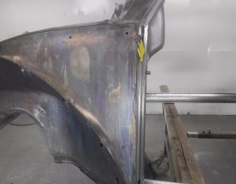 Bare metal car fender on workshop stand
