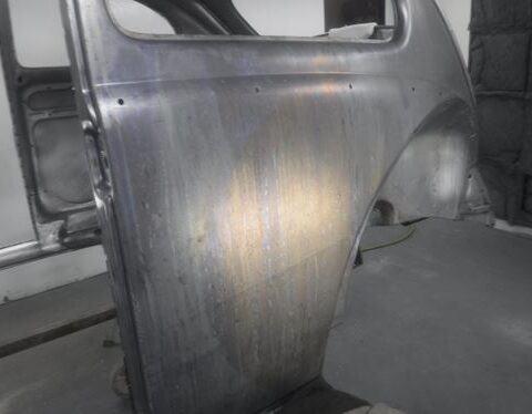 Bare metal car door panel in workshop