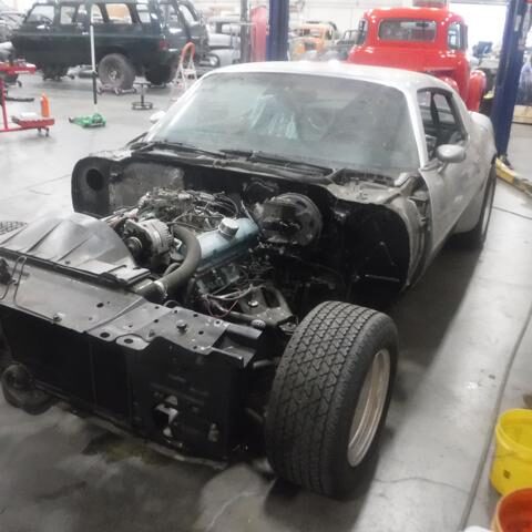 Classic car undergoing engine restoration in a workshop.