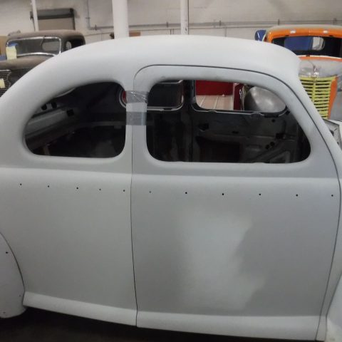 Primered vintage coupe undergoing restoration in garage