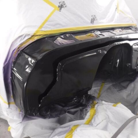 Freshly painted black car bumper in paint booth