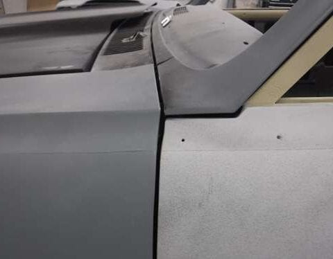 Close-up of primered car hood and pillar