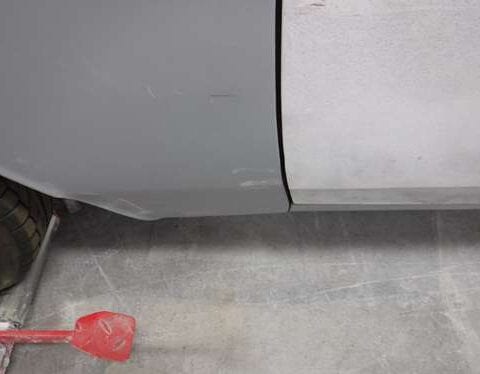 Car door panel primed and sanded near wheel