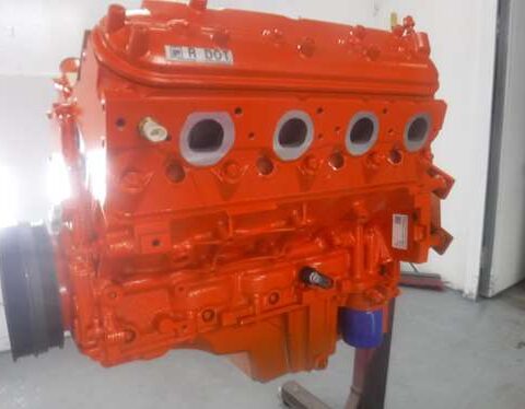 Bright orange painted engine block with visible openings and parts.