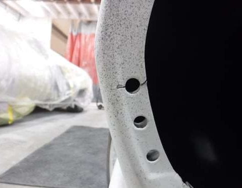 Close-up of drilled holes in white car fender