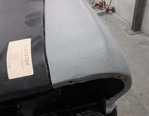 Primed car fender beside black hood