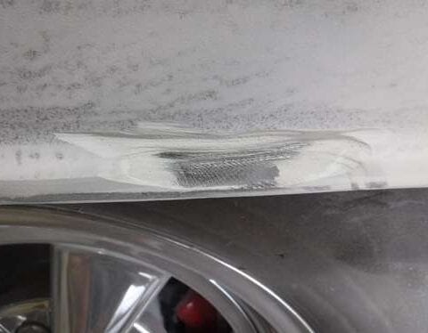 Scuffed white car bumper with scraped paint