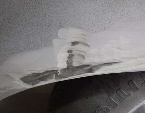 Scraped car wheel arch with filler and tire