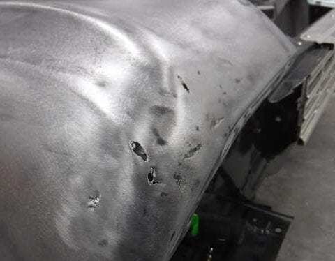 Dented car fender with rusted holes