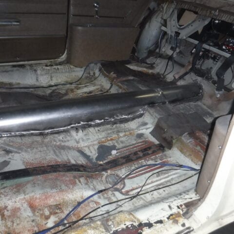 Stripped car interior showing rusted floor pan