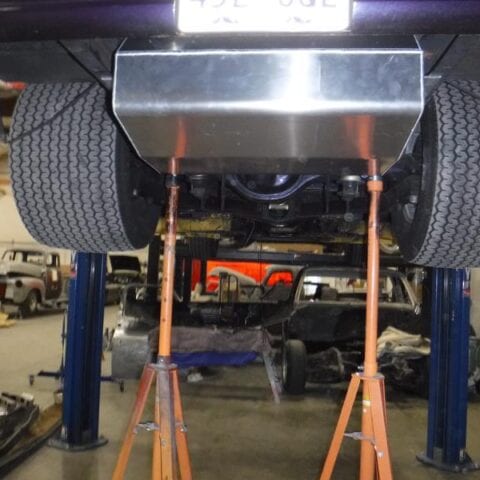 Car underside on lift with orange jack stands