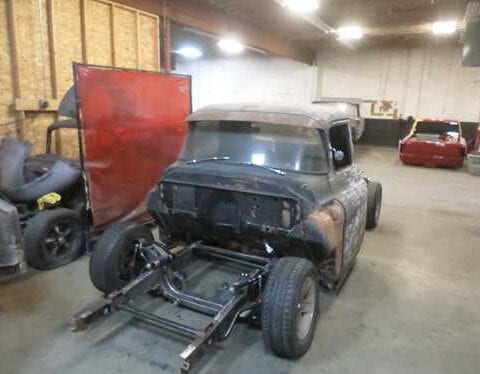 Vintage car restoration in garage with exposed chassis