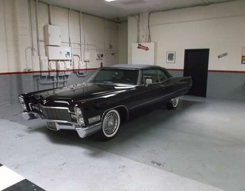 Classic black vintage car parked indoors with whitewall tires.